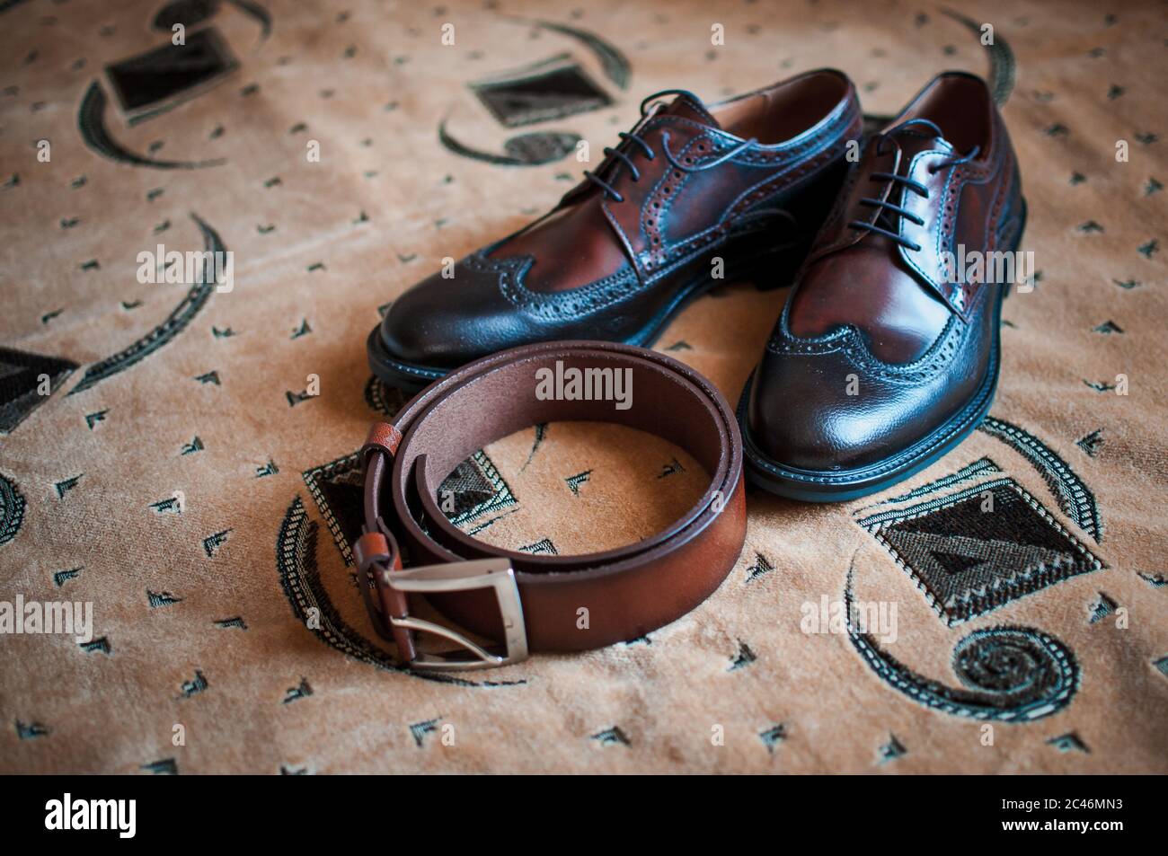 Herrenschuhe und brauner Gürtel auf dem Teppich Stockfoto