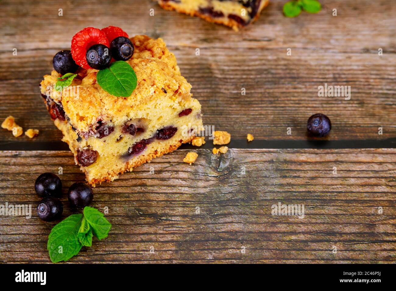 Stück Blaubeerkuchen mit frischen Beeren auf Holzhintergrund. Stockfoto