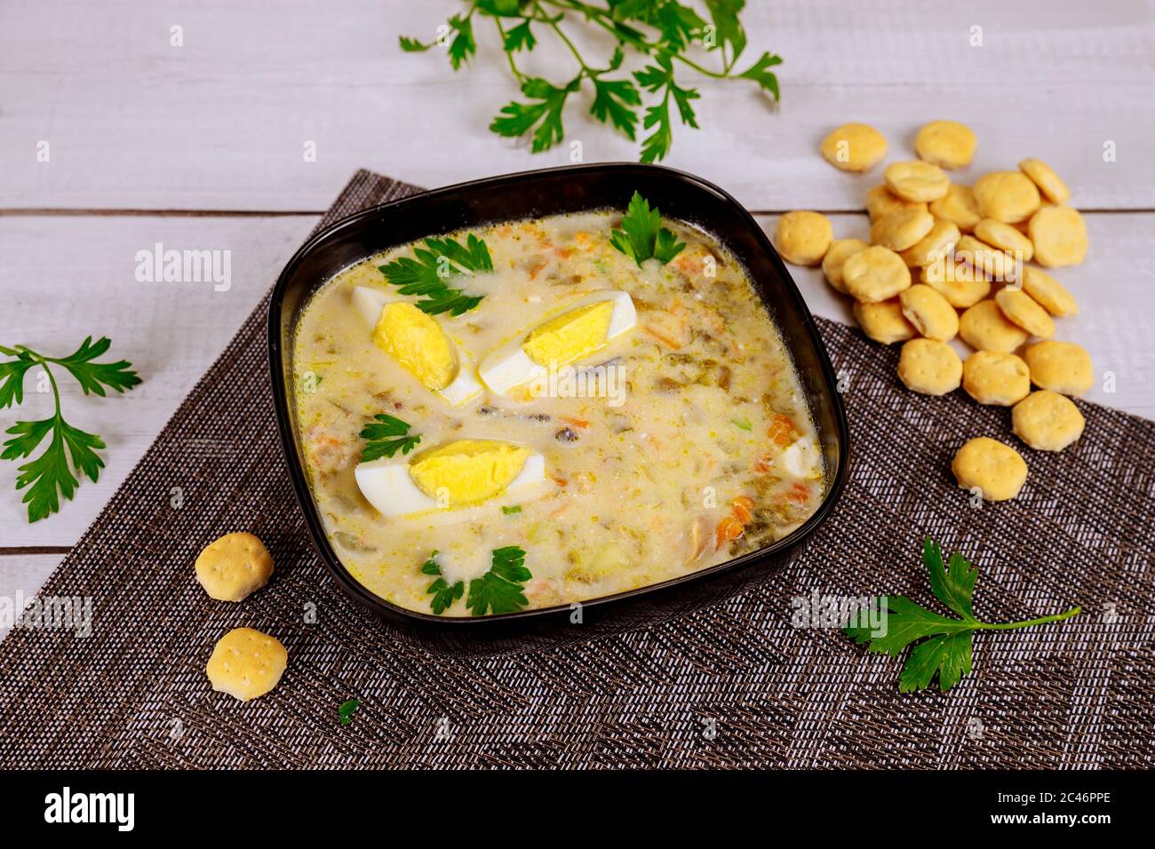 Cremige Gemüsesuppe in schwarzer Schüssel mit Ei und Crackern. Chinesische Küche. Stockfoto