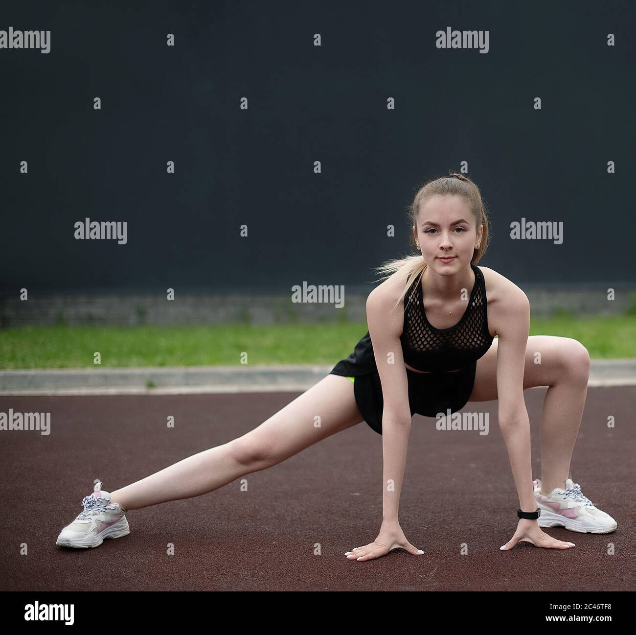 Ein schönes athletisches Mädchen ist im Sommer in Outdoor-Fitness beschäftigt. Ein junges Mädchen streckt und wärmt sich in der Sportarena auf. Ein attraktives Mädchen Stockfoto