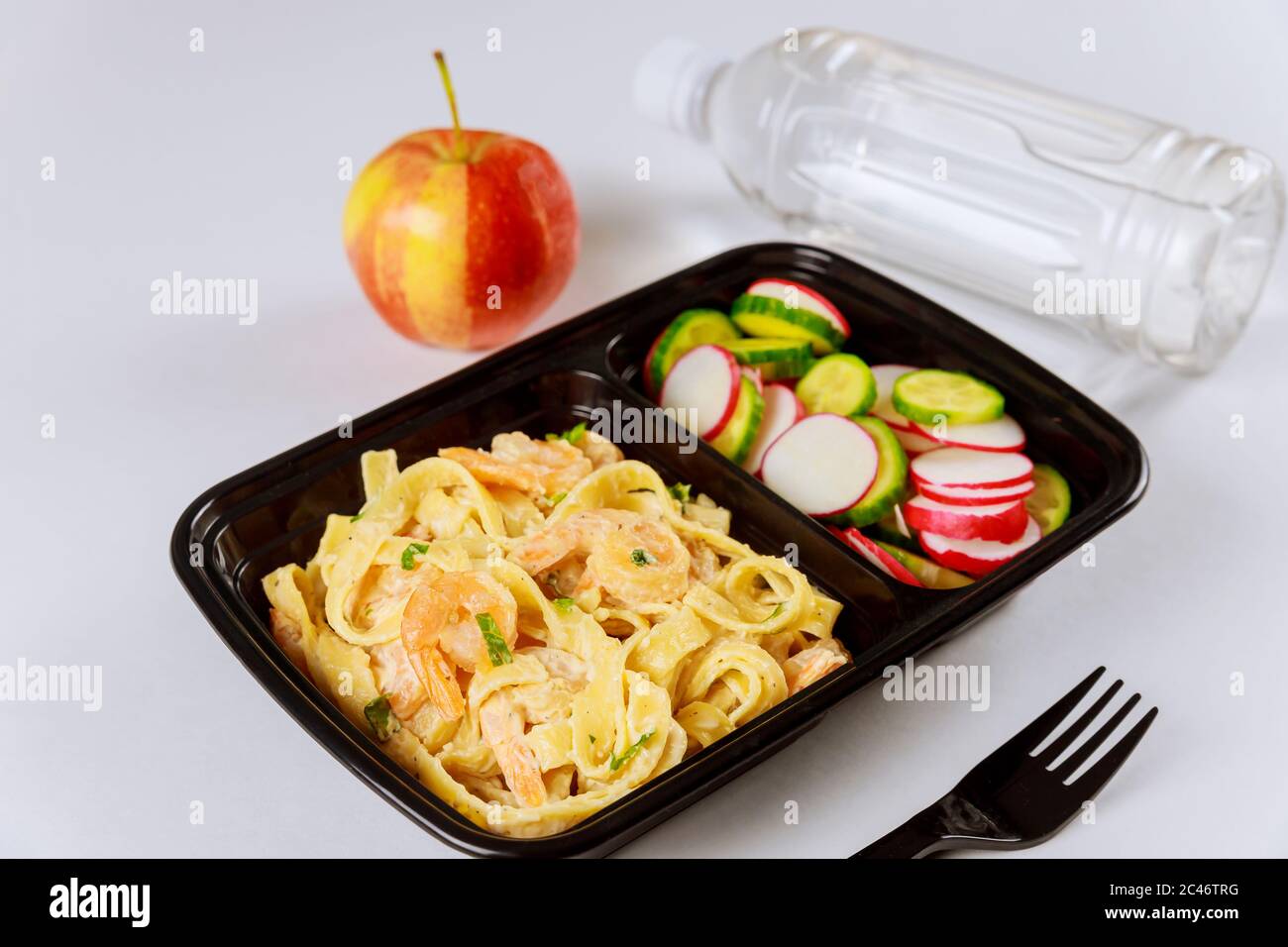 Schwarzer Plastikbehälter mit Nudeln, Garnelen und frischem Salat. Lieferung von Lebensmitteln. Stockfoto