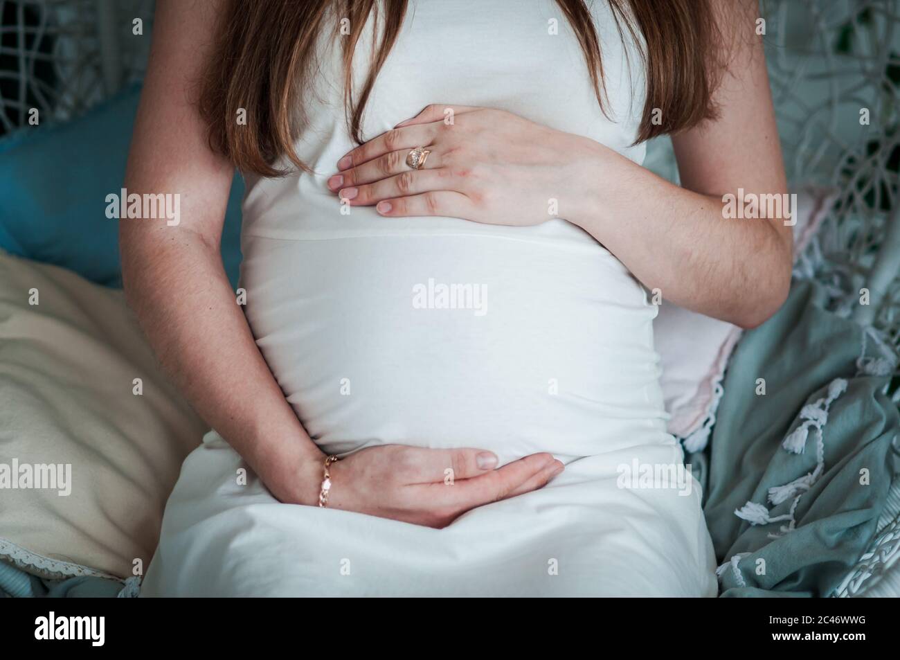 Schwangere Frau in weißem Kleid und Mann umarmen Bauch Stockfoto