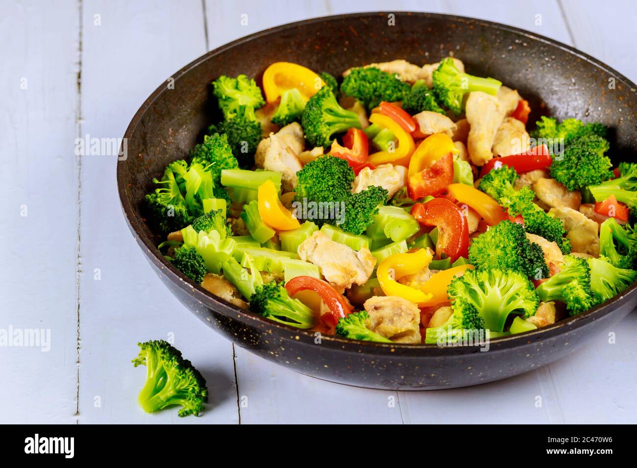 Schmackhafte gesunde rühren braten Gemüse mit Huhn in der Pfanne auf weißen Holzoberfläche. Stockfoto