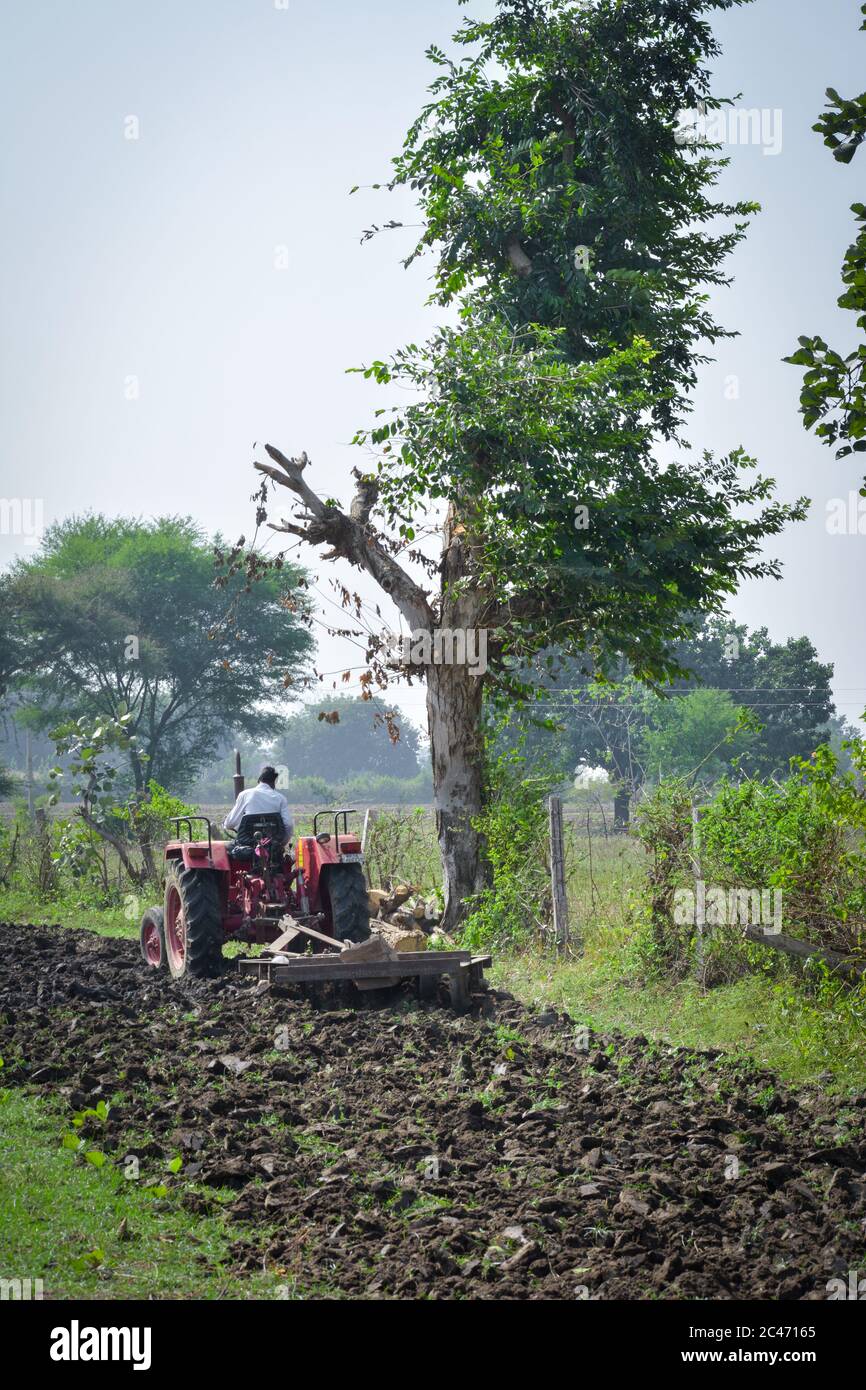 TIKAMGARH, MADHYA PRADESH, INDIEN - 10. NOVEMBER 2019: Indischer Bauer mit Traktor, der Land für die Aussaat mit Egge vorbereitet. Stockfoto