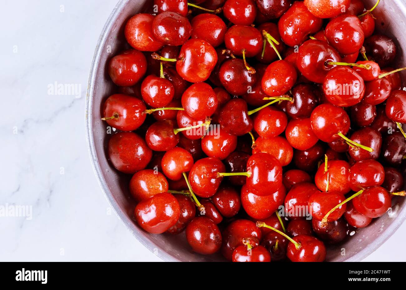 Frische Bio-Kirschen mit Stiel in Sieb auf weißem Hintergrund. Nahaufnahme. Stockfoto