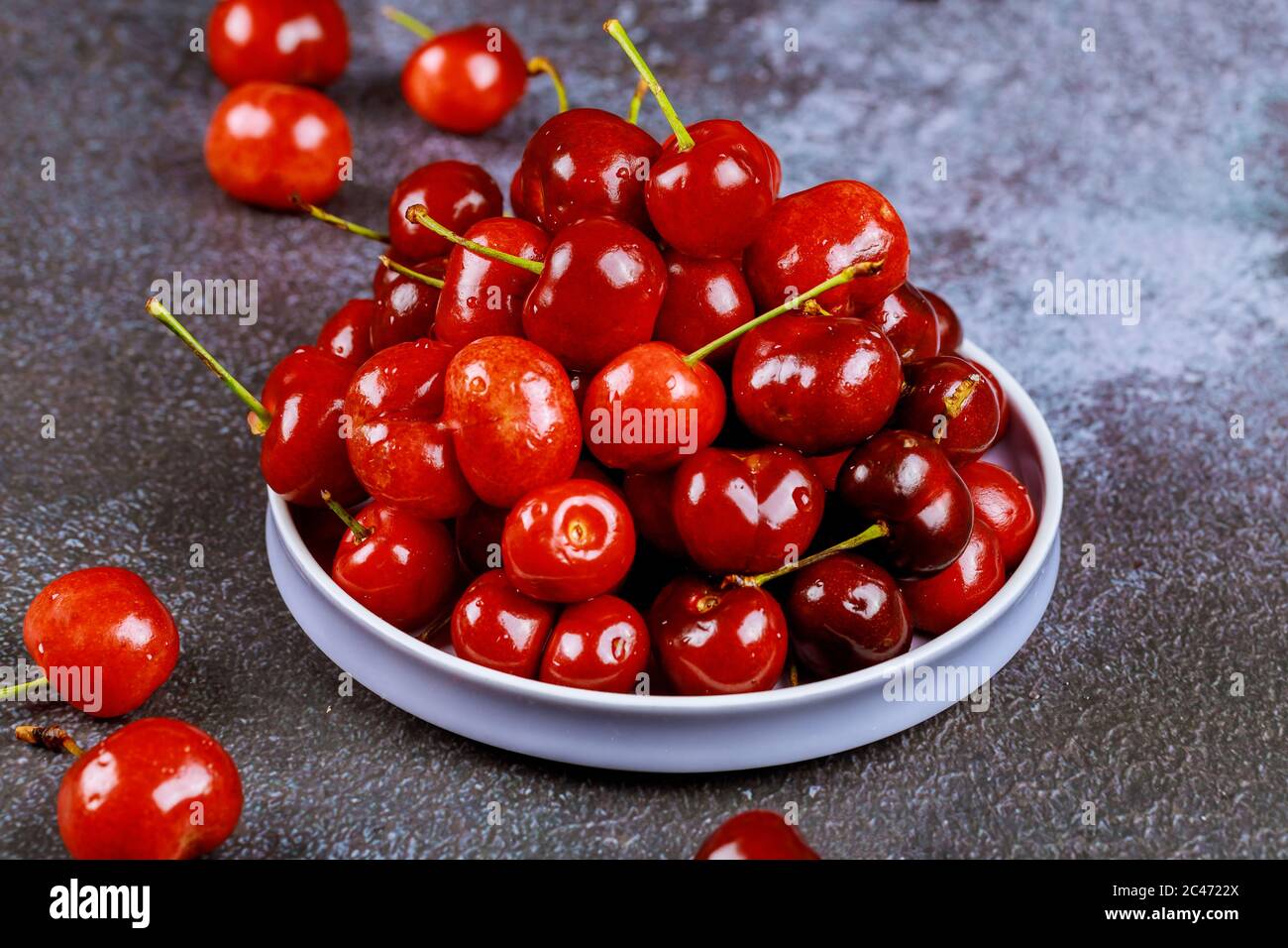 Süße rote Kirschen auf einem Teller auf dunklem Hintergrund. Nahaufnahme. Stockfoto