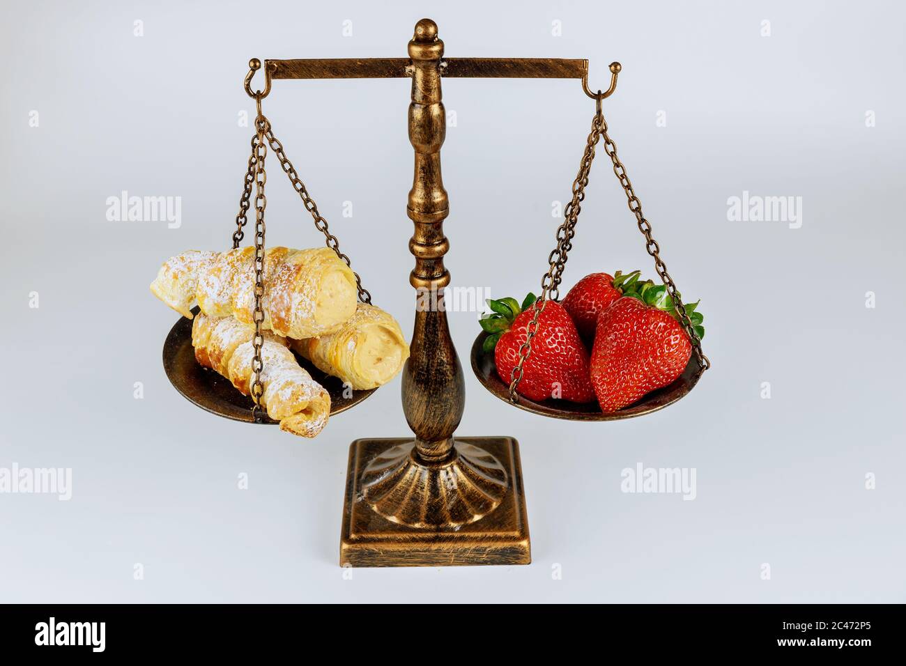 Waage mit gesunden und ungesunden Lebensmitteln auf weißem, isoliertem Hintergrund. Stockfoto