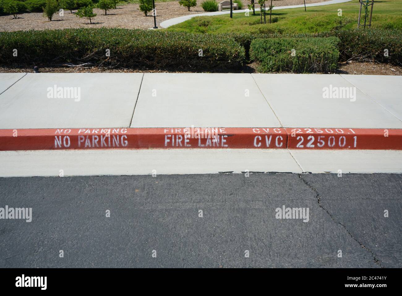 Nahaufnahme der rot gestrichenen Bordsteinkante mit Text „Fire Lane“. Stockfoto