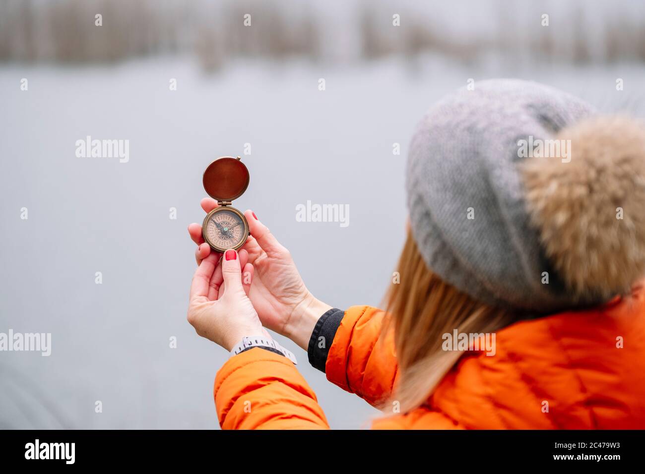 Eine touristische Frau in Hut und Mantel mit einem Kompass in der Natur Stockfoto