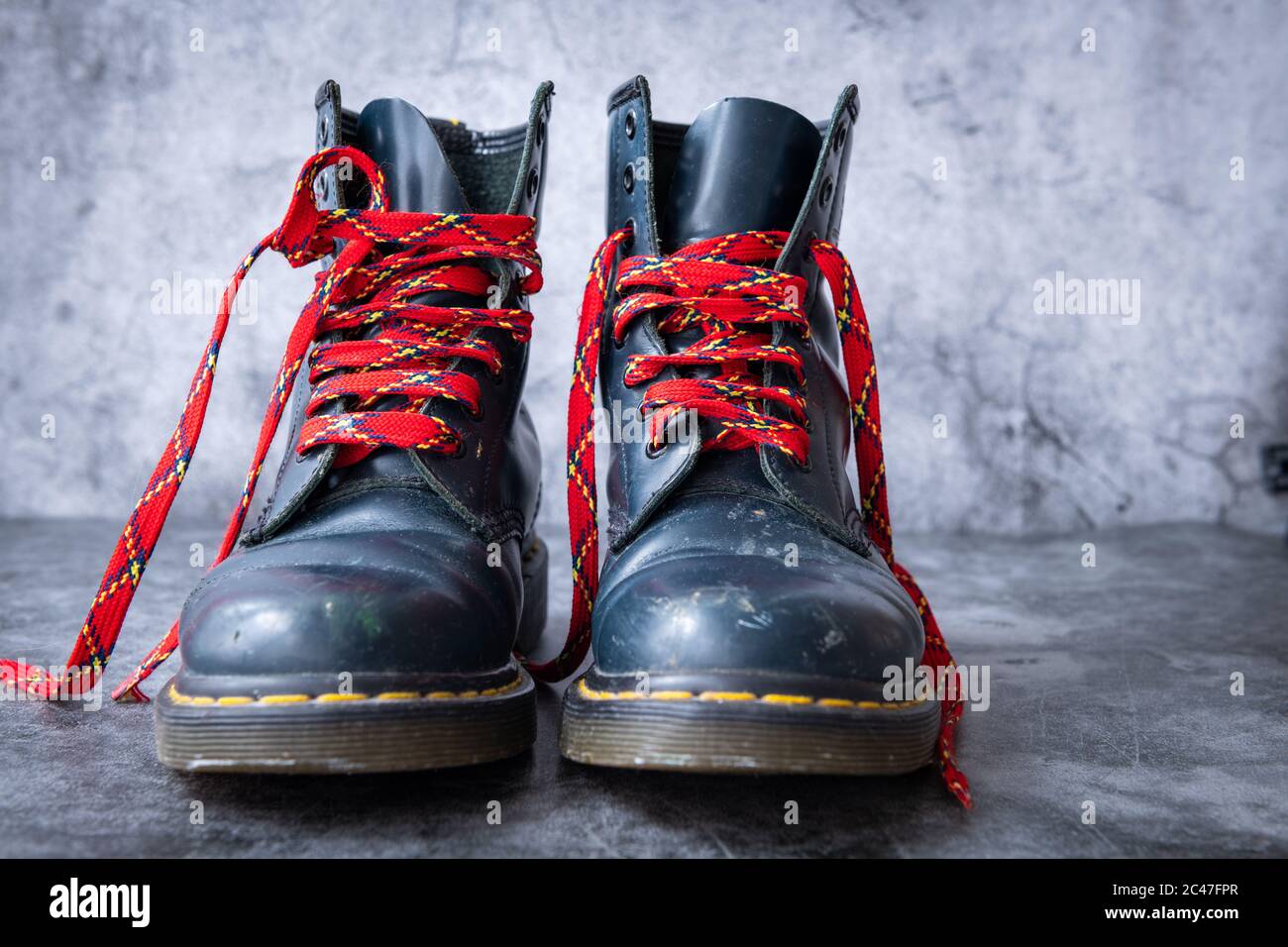 Ein Paar gebrauchte schwarze Leder tiefe Stiefel mit roten Schuh  Schnürsenkel in einem grauen Hintergrund Stockfotografie - Alamy