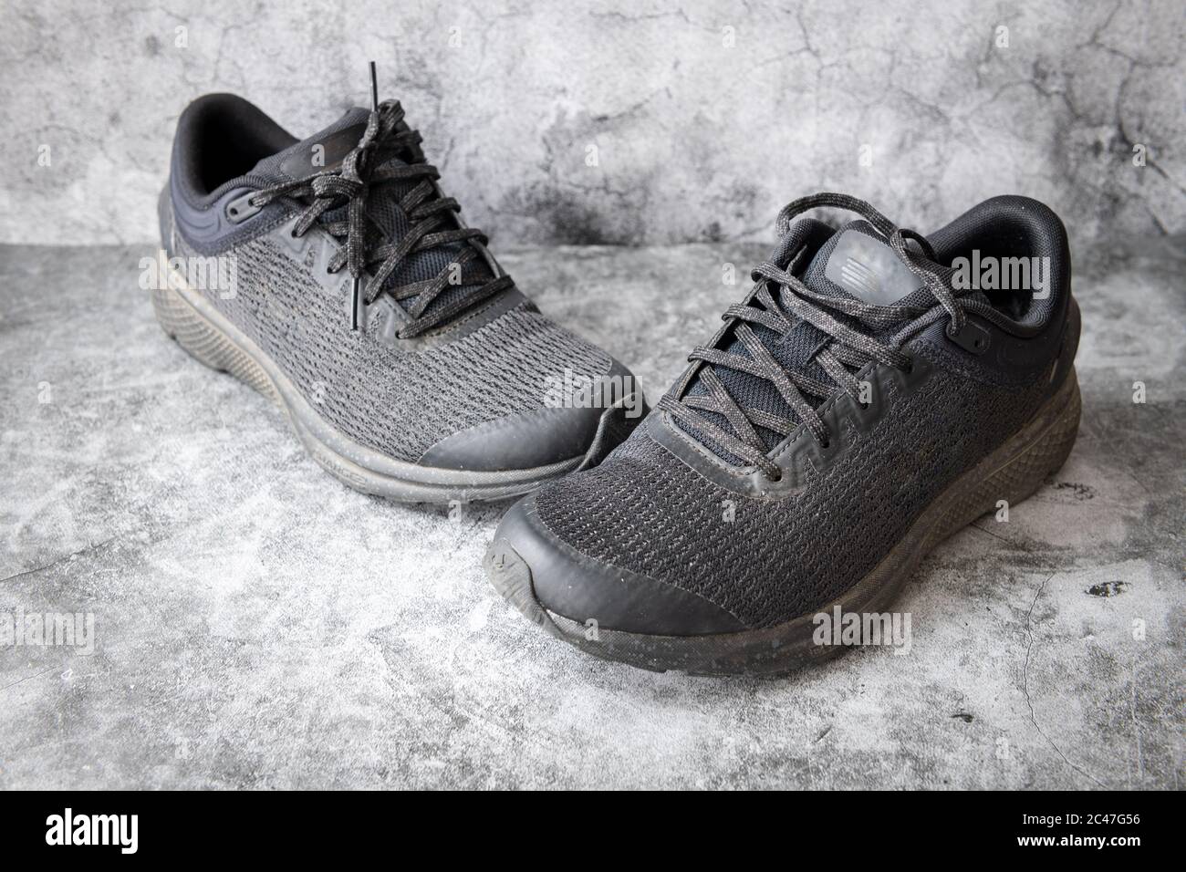 Ein Paar schwarze Turnschuhe, Laufschuhe in einem grauen Beton Hintergrund. Stockfoto