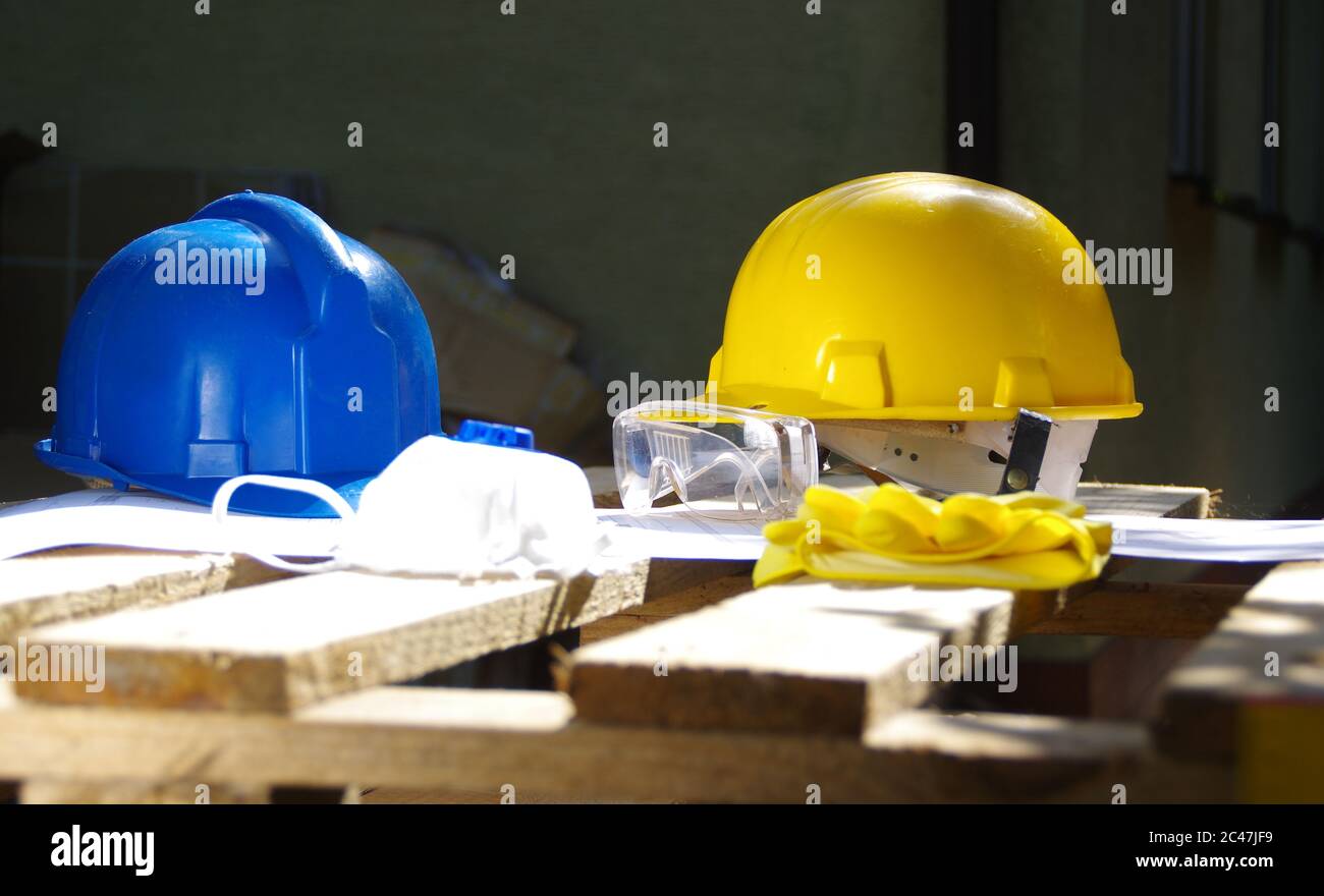 Gelber und blauer Schutzhelm. Persönliche Schutzausrüstung. Sicherheit auf der Baustelle. Stockfoto