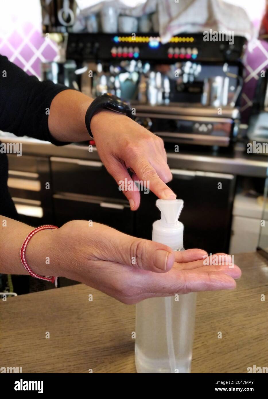 Barista in einem Café, der Desinfektionsmittel auf die Hände aufgibt Stockfoto