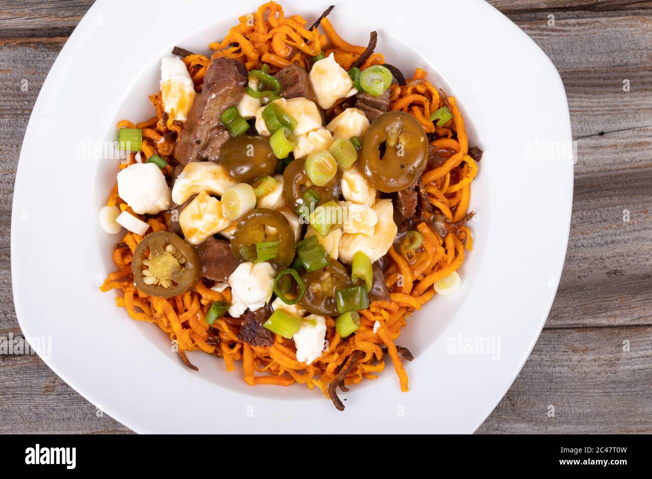 Süßkartoffel Jalapeno und Rindfleisch Steak poutine kanadische Gericht mit grünem Oignon gekrönt Stockfoto