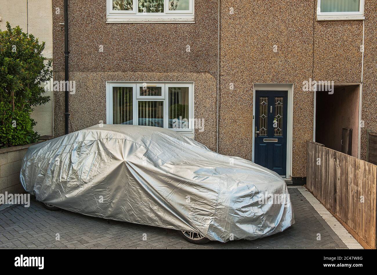 Großes Auto geparkt außerhalb kleines Haus mit Silber Kunststoff-Abdeckung geschützt. Stockfoto