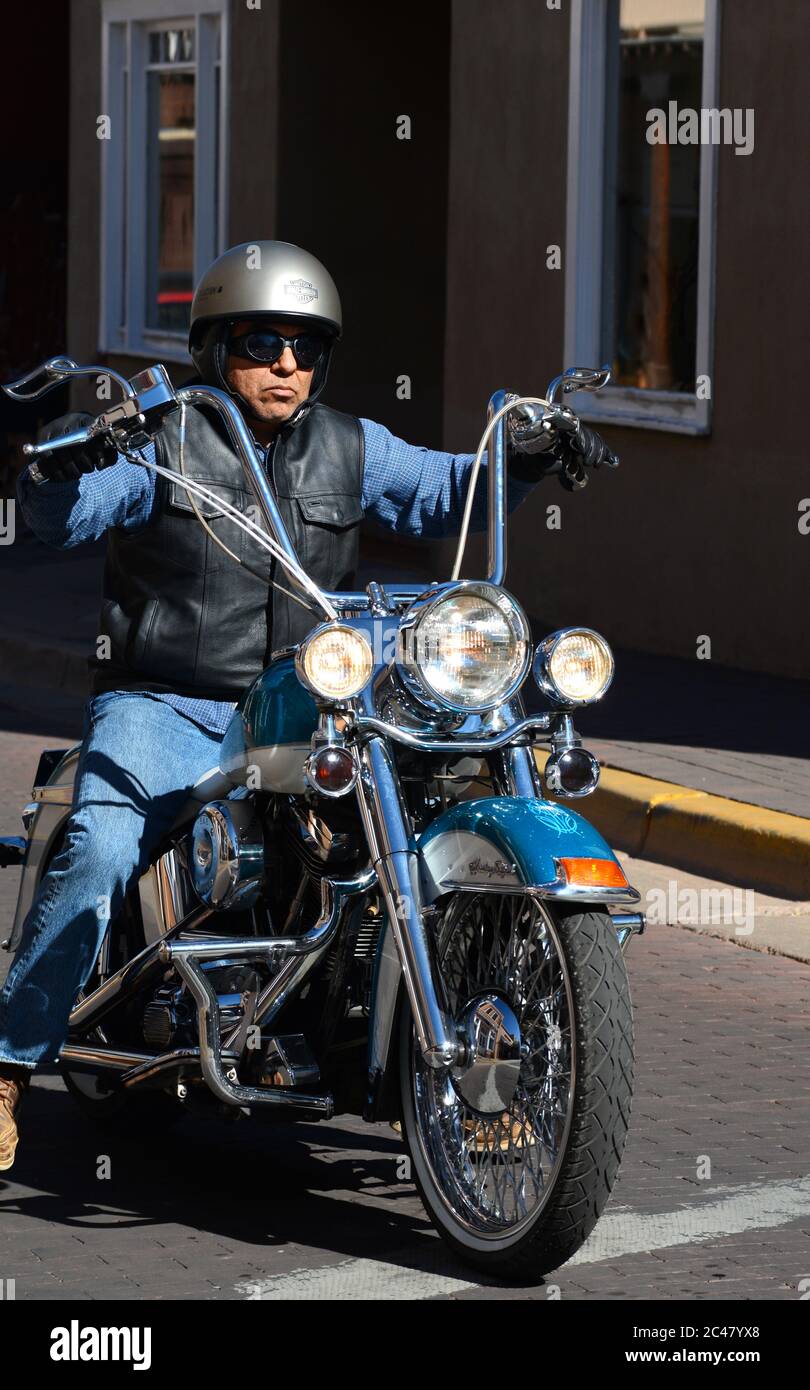 Ein Mann, der ein kundenspezifisches Harley-Davidson Motorrad mit Affe-Hanger-Lenker reitet, fährt entlang einer Straße in Santa Fe, New Mexico. Stockfoto