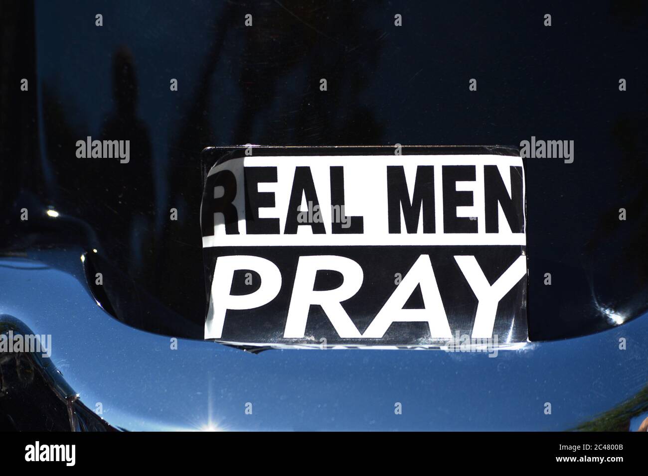 Ein Aufkleber auf der Rückseite eines Harley-Davidson Motorrads erklärt, dass 'Real Men Pray'. Stockfoto