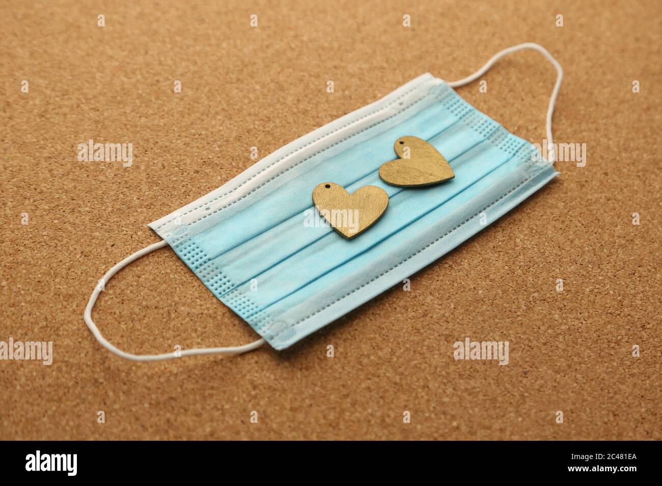 Zwei Holzherzen auf einer medizinischen Gesichtsmaske. Stockfoto