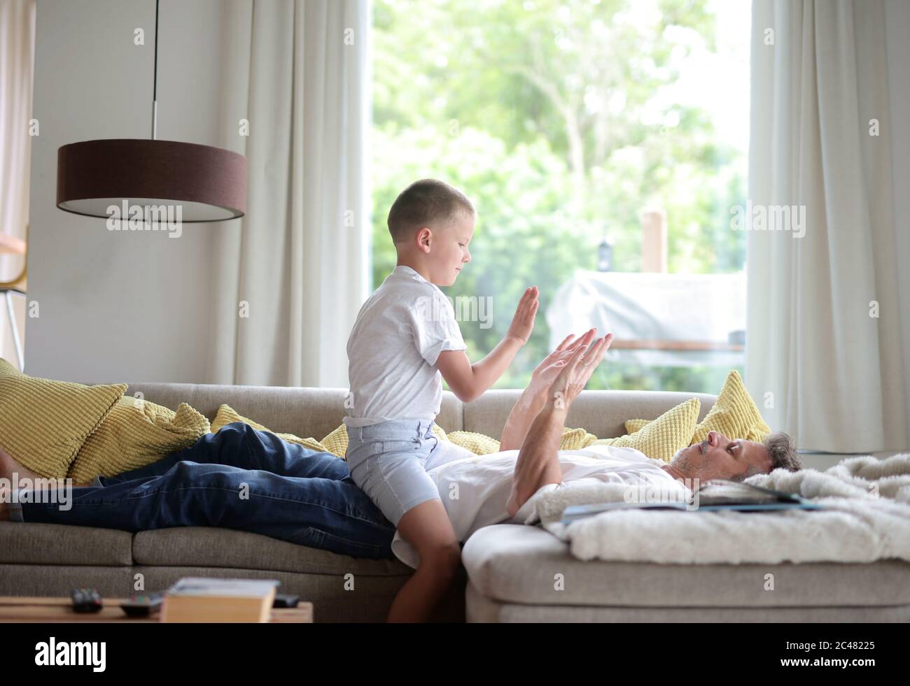 Kleiner Junge, der mit seinem Vater auf dem Sofa spielt Das Wohnzimmer Stockfoto