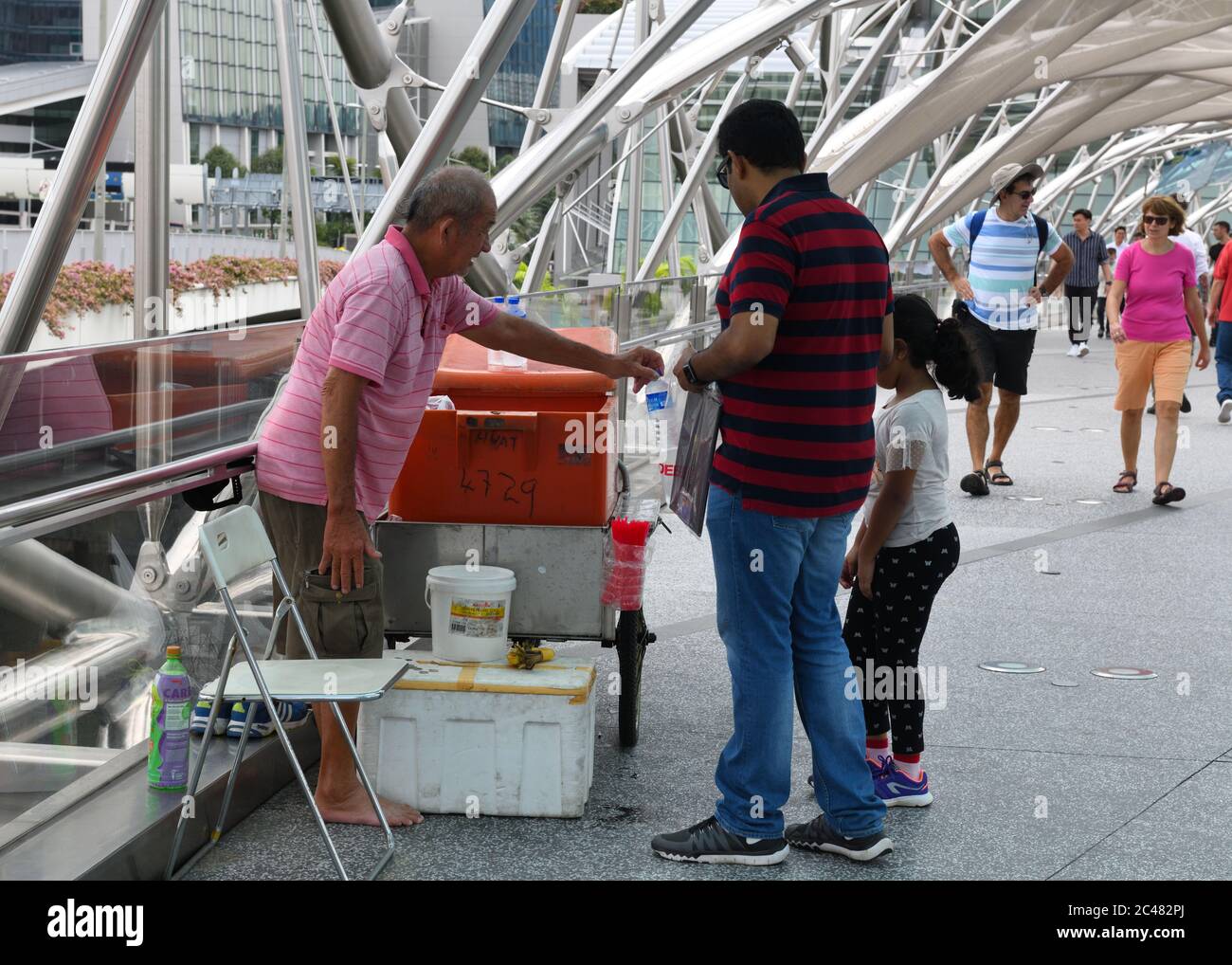 Ein Mann verkauft kaltes Wasser in Flaschen auf der Helix-Brücke in Singapur, Asien Stockfoto