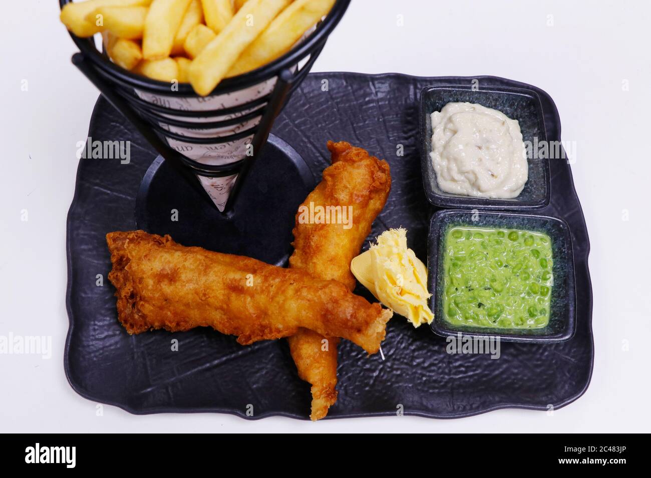 Gebratener Fisch mit Tatarsauce, matschiger Erbsen und Kartoffelchips, bekannt als Fisch und Pommes Stockfoto