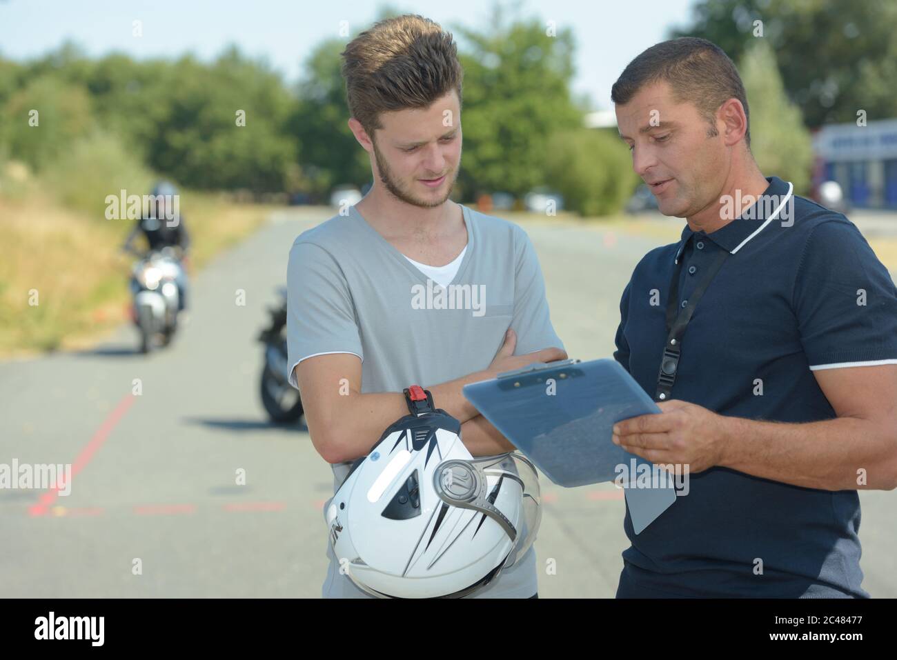 Junger Mann im Gespräch mit dem Ausbilder auf Motorrad-Trainingskurs Stockfoto