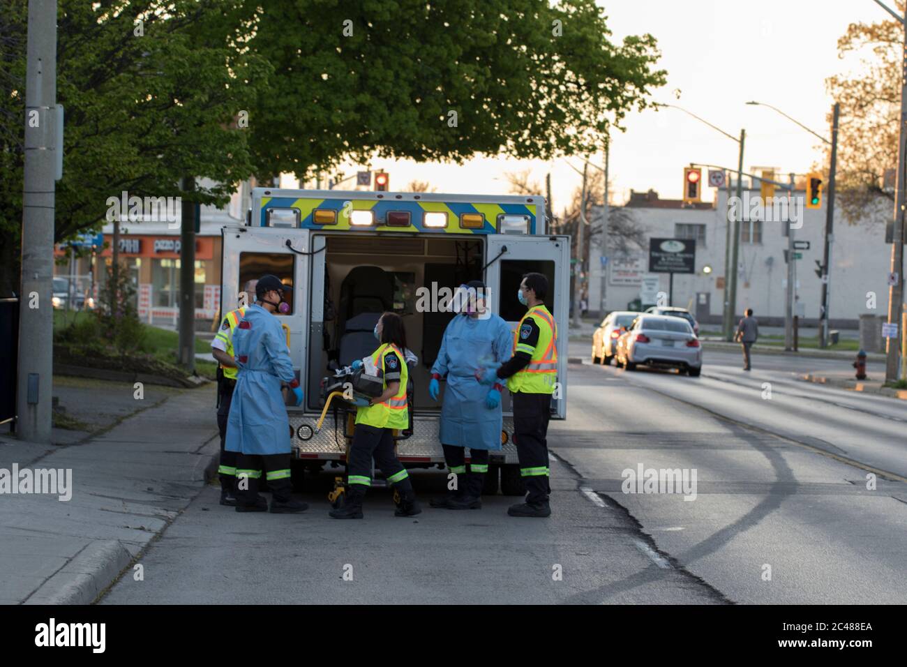 Sanitäter mit PSA Vorbereitung auf die Entfernung von infizierten Senioren aus betreuten Wohnheims nach Covid-19 Ausbruch infiziert über 60 Menschen. Stockfoto