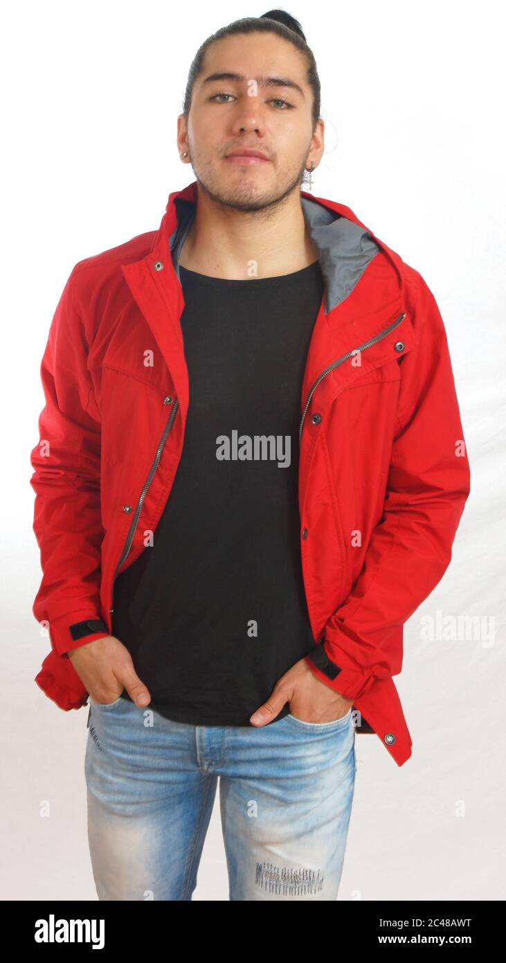 Junger hispanic Mann mit gerafften Haaren fertig Bogen trägt schwarzes T-Shirt und rote Jacke, Hände in Taschen von Hosen, posiert mit Blick auf die Kamera auf weißem Rücken Stockfoto