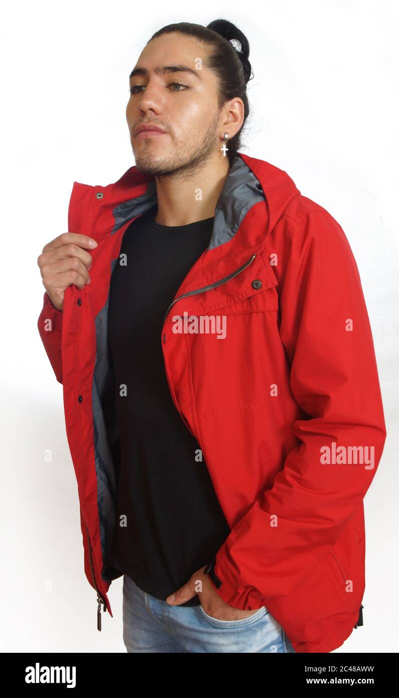 Junger hispanic Mann mit gerafftem Haar fertig Bogen trägt schwarzes T-Shirt und rote Jacke, mit einer Hand auf seiner Hosentasche, Blick links auf weißen Rückenausschnitt Stockfoto