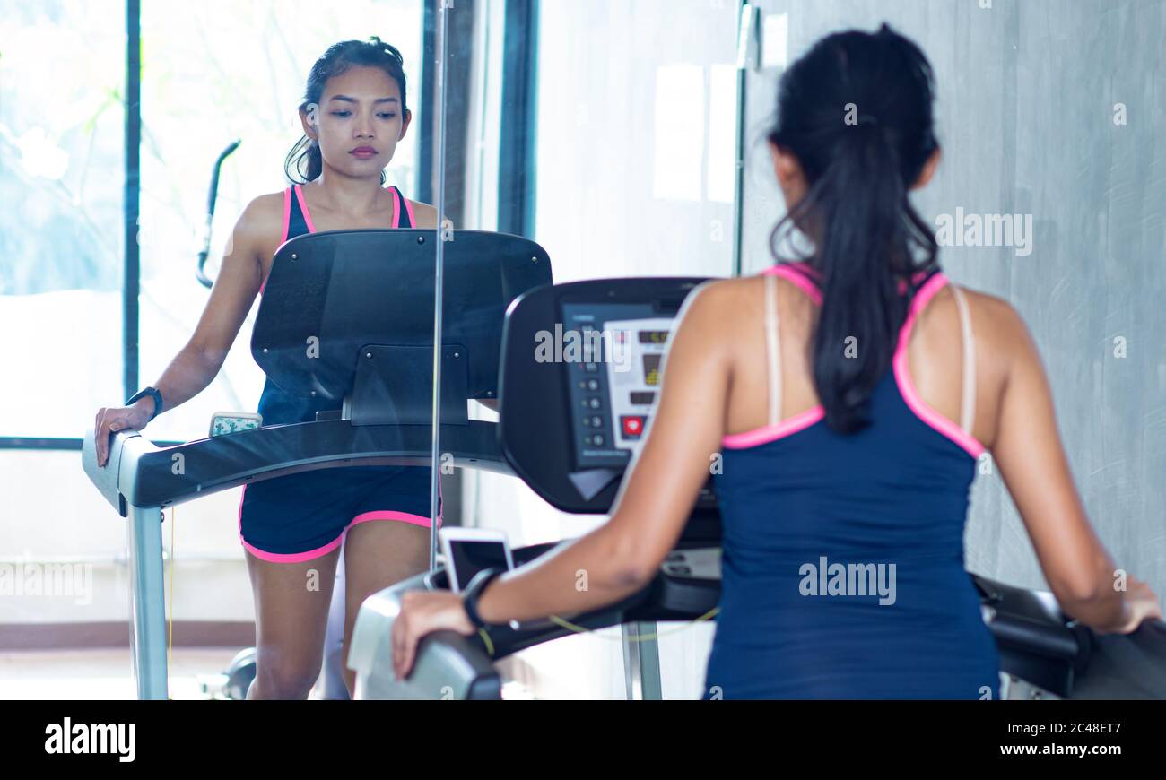 Junge Frau üben in der Turnhalle mit Spiegeln. Mädchen, die auf Laufband bei Fitness Club. Stockfoto