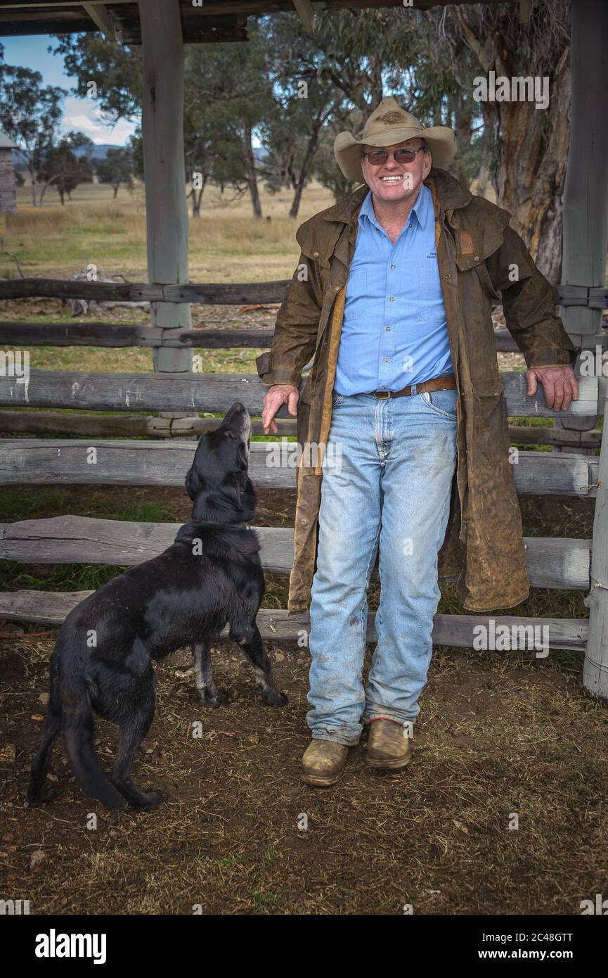 Der Manager der Schafstation hält lächelnd zurück an der Kamera, während sein treuer Schafhund neben ihm auf der Laura Station, New South Wales, Australien, steht. Stockfoto