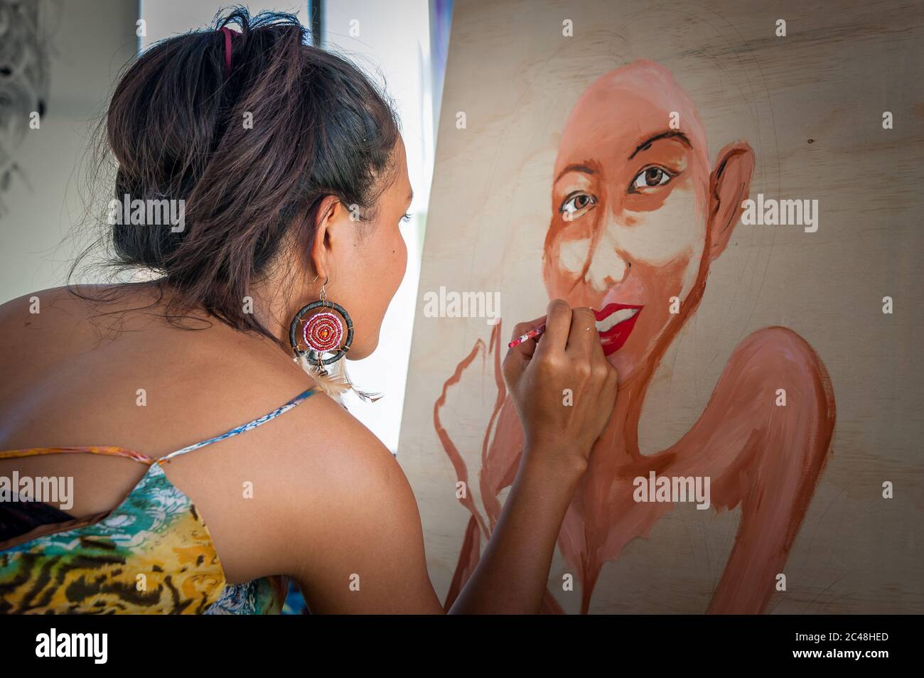 Eine thailändische Künstlerin auf den Port Douglas Markets in Far North Queensland in Australien konzentriert sich auf die Vervollständigung eines stilistischen Porträts. Stockfoto