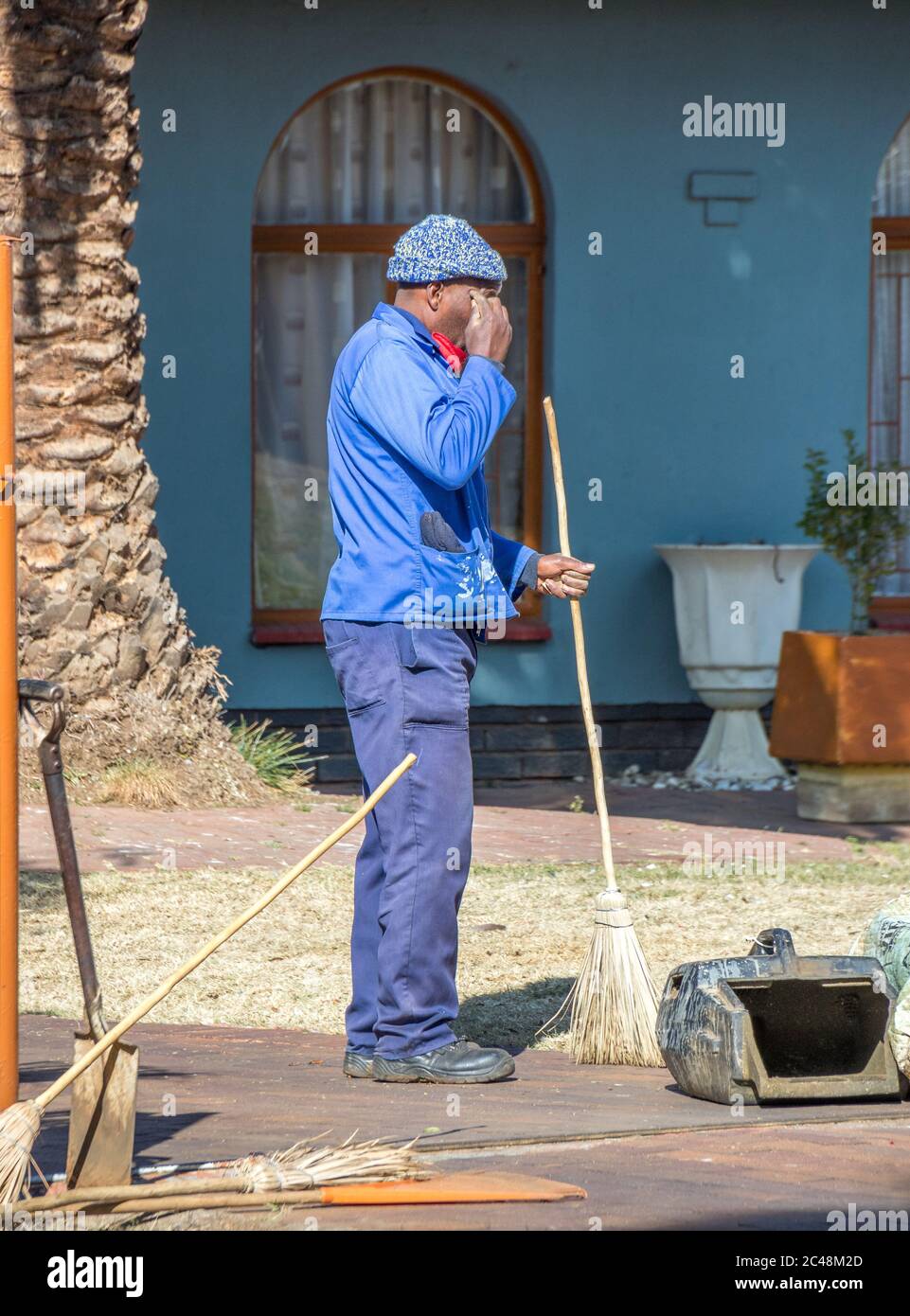 Alberton, Südafrika - unidentifizierter schwarzer Mann arbeitet in einem Wohngarten als Arbeit, um ein lebendiges Bild in vertikalem Format zu verdienen Stockfoto
