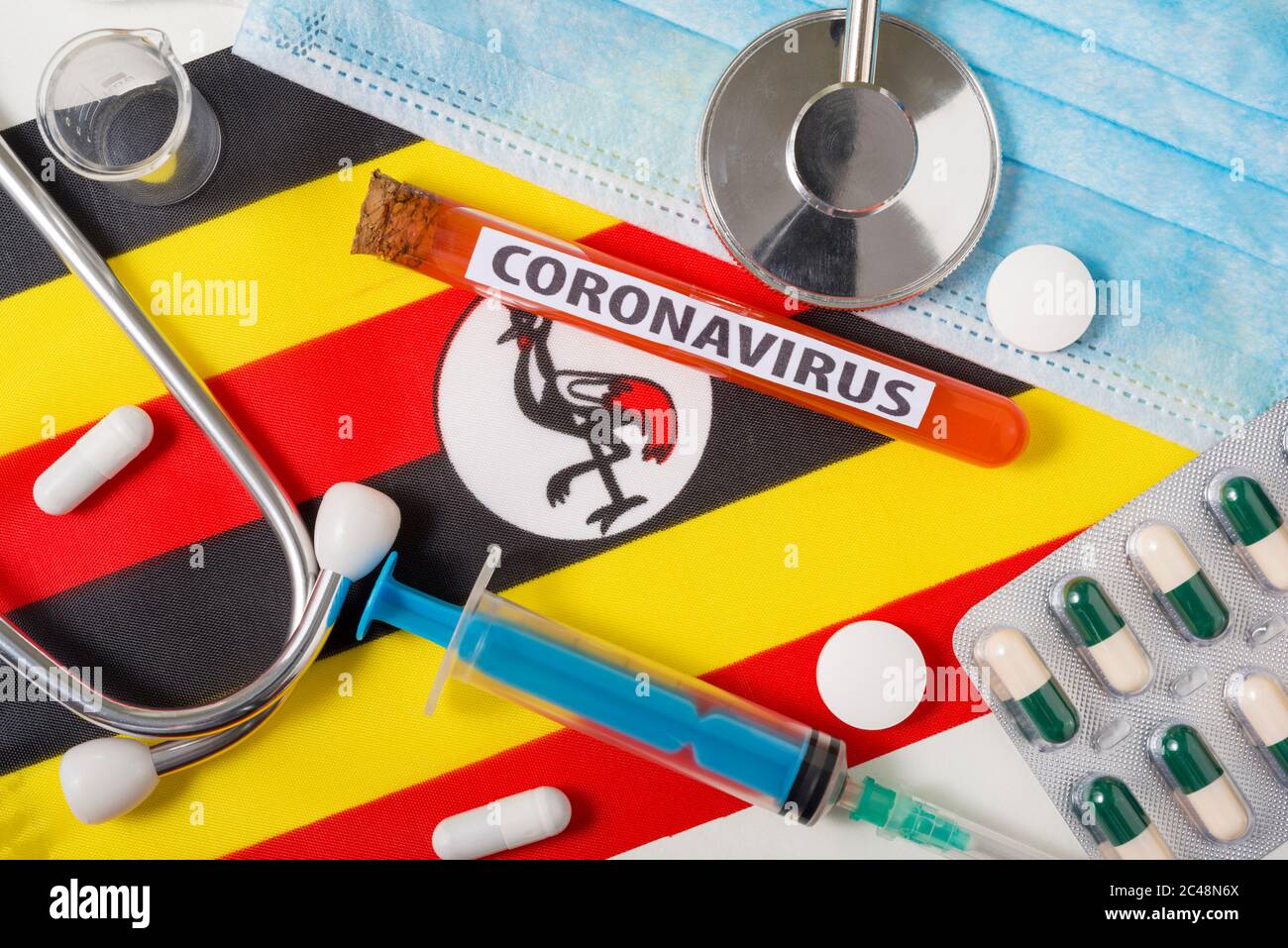 Coronavirus, nCoV-Konzept. Draufsicht schützende Atemmaske, Stethoskop, Spritze, Tabletten auf der Flagge Ugandas. Ein neuer Ausbruch des chinesischen coro Stockfoto