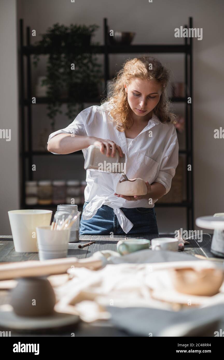 Produktionsprozess der Keramik. Anwendung der Glasurbürste auf Keramikgeschirr. Stockfoto