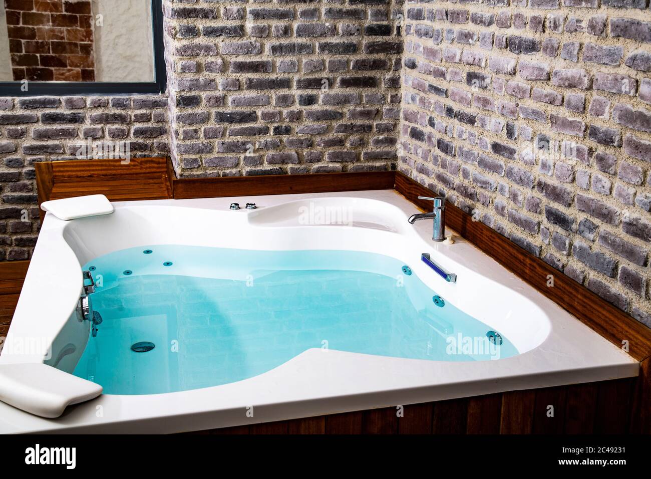 Das Innere des Badezimmers. Ein großes Jacuzzi-Bad steht in der Mitte eines hellen, geräumigen Steinzimmers dekoriert. Modern, Öko, Fenster, Grün. Stockfoto