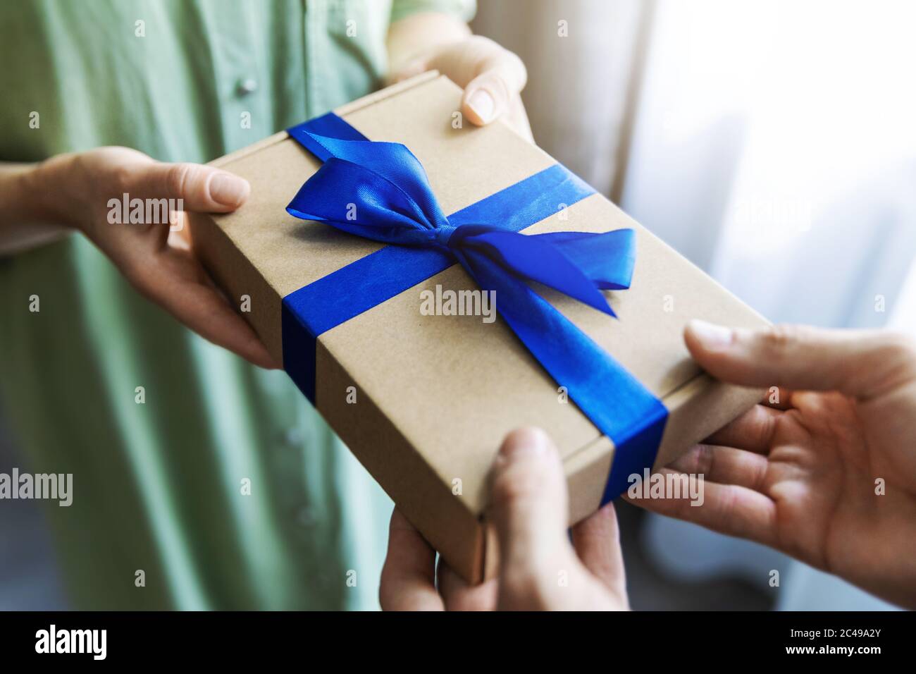 Mann, der Frau Geschenkbox mit blauem Band gibt Stockfoto