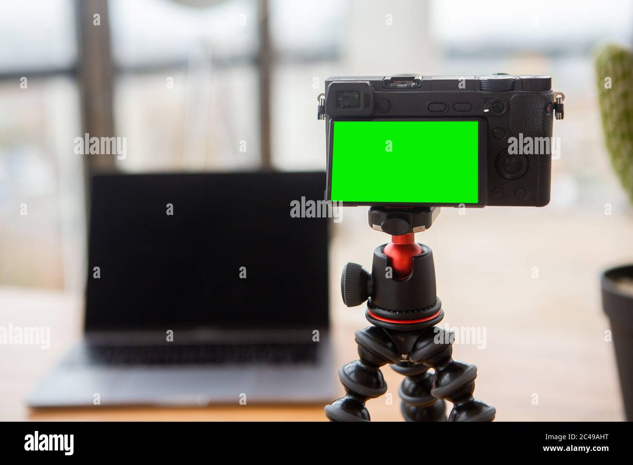 Kamera mit grünem Bildschirm und Laptop hinten für Video-Blogging Stockfoto