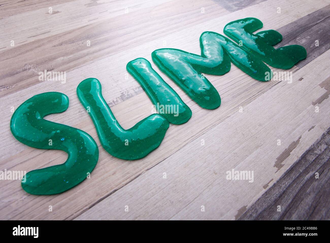 Schleimtext aus transparentem Schleim diagonal auf einer Holzfläche Stockfoto