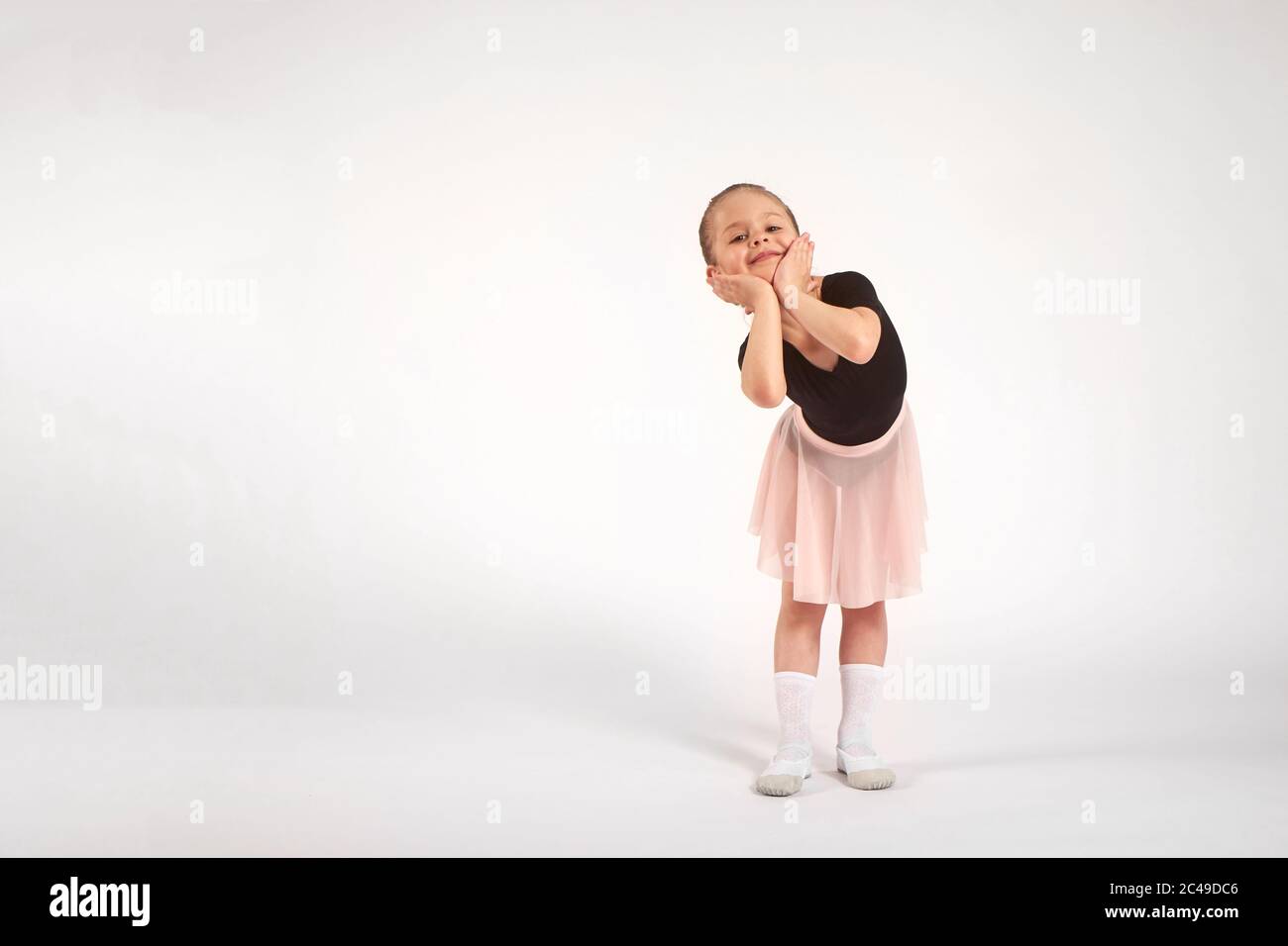 Kleines Mädchen in Tanzuniform tanzt auf weißem Hintergrund im Studio Stockfoto