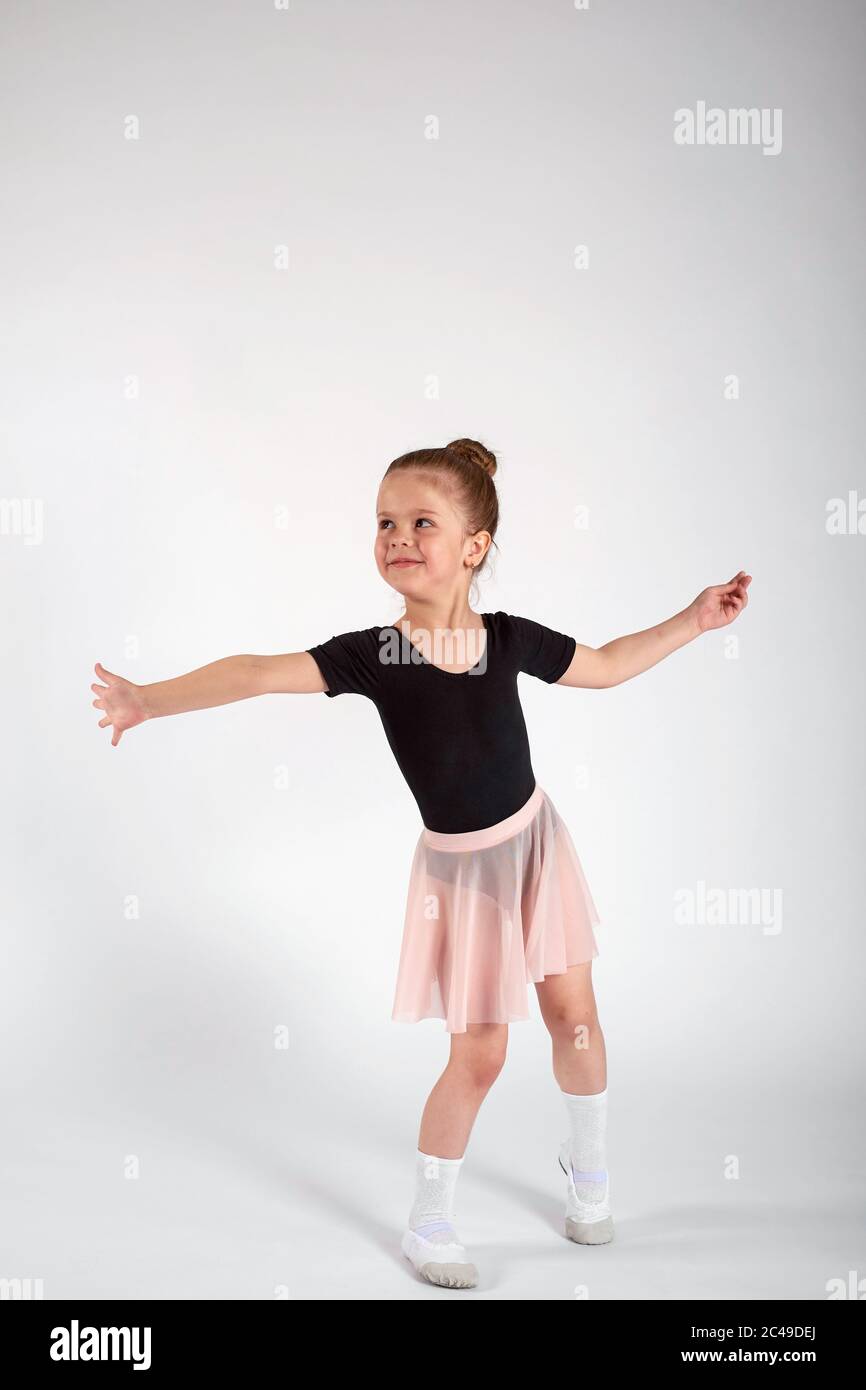 Kleines Mädchen in Tanzuniform tanzt auf weißem Hintergrund im Studio Stockfoto