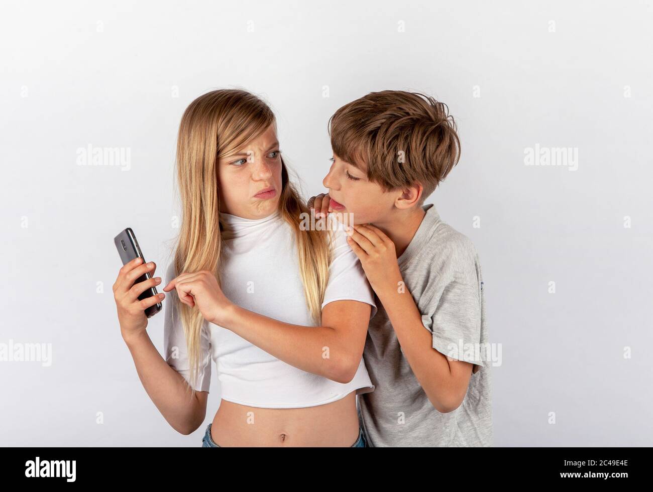 Junge versucht, ein Mädchen Handy beobachten von ihrer Schulter aus, aber das Mädchen bemerkte es und wurde sehr wütend Stockfoto