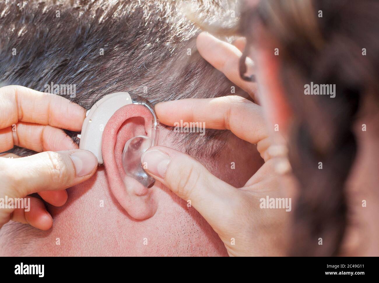 Frau hilft beim Einsetzen eines Hörgeräts Stockfoto