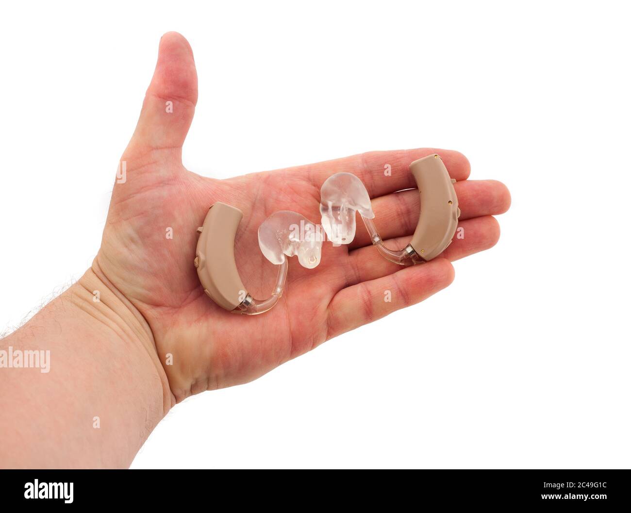 Hand des Mannes, der ein Paar BTE-Hörgeräte mit Ohrmugelform hält Stockfoto