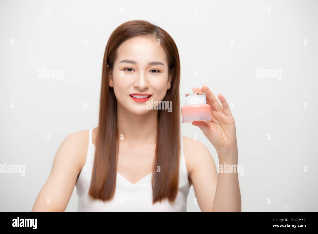 Lächelnde asiatische Frau zeigt Hautpflege, Kosmetikprodukte. Stockfoto