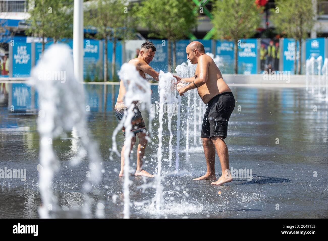 Zwei Männer, die Spaß in den Wasserfontänen, Centenary Square, Birmingham UK Stockfoto