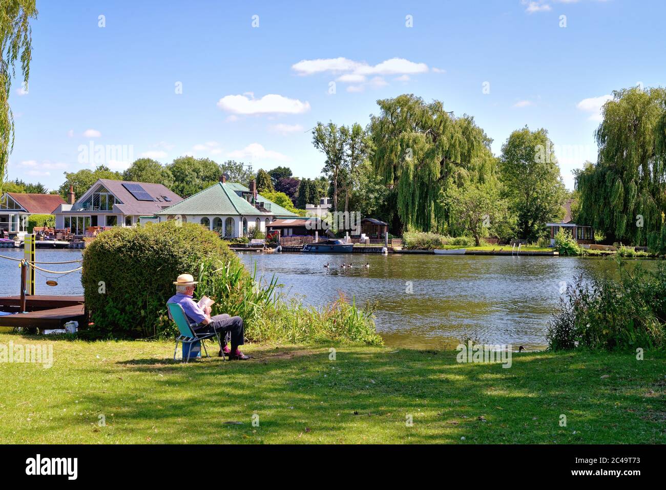 Ein älterer Herr, der sich an einem heißen Sommertag am Flussufer in Shepperton Surrey UK entspannt Stockfoto