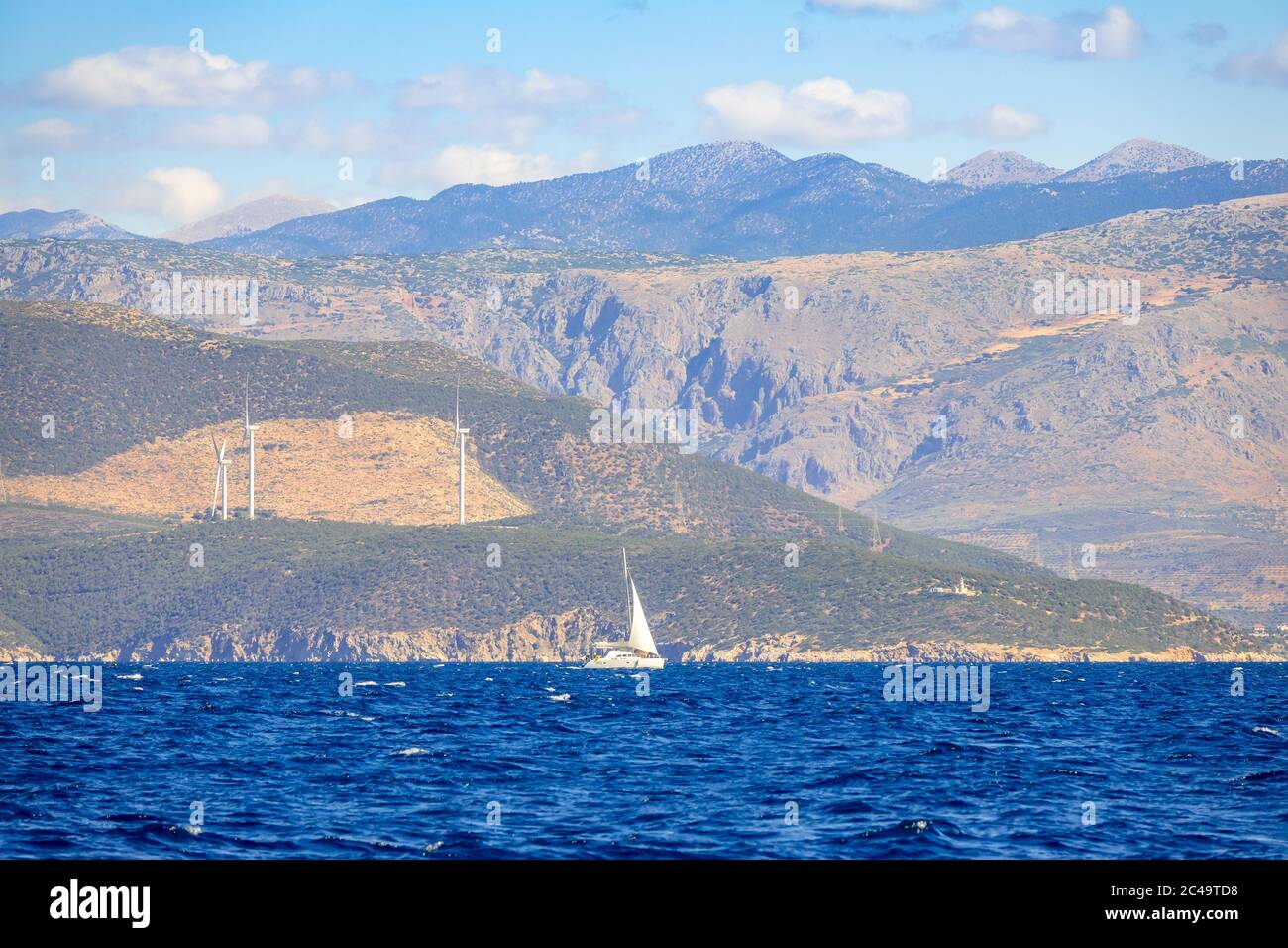 Einsame Segelyacht an sonnigen Sommertagen und die hügelige Küste mit Windparks Stockfoto