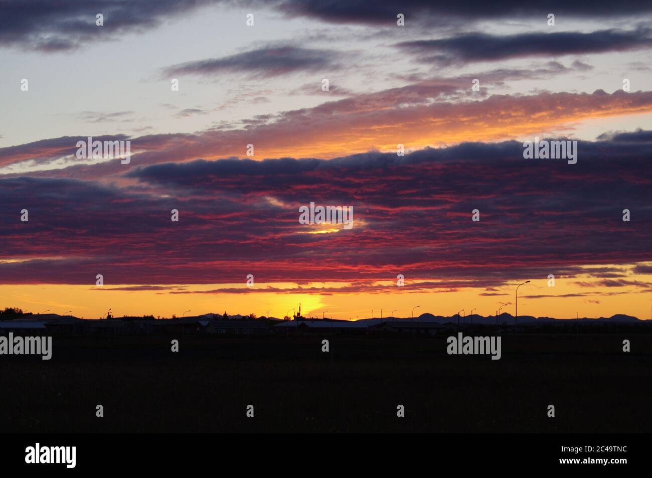 Magentafarbene Wolken bei Sonnenuntergang über Silhouette Horizont,Bildfolge eines Sonnenuntergangs,Blauer Himmel mit magentafarbenen Wolken bei Sonnenuntergang,untergehende Sonne Magentafarben Wolken, Stockfoto