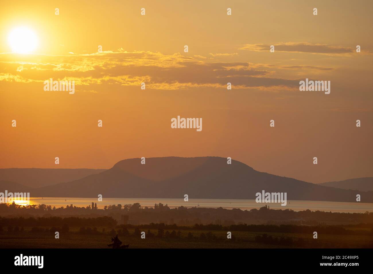 Sonnenuntergang mit Lichtreflexe über dem Plattensee und Badacsony Berg in Ungarn Stockfoto